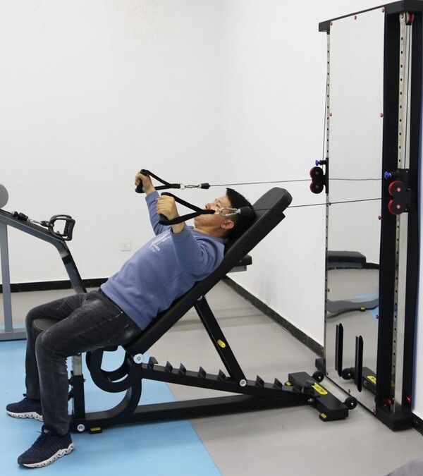Man on weight bench in front of wall mounted functional trainer mirror