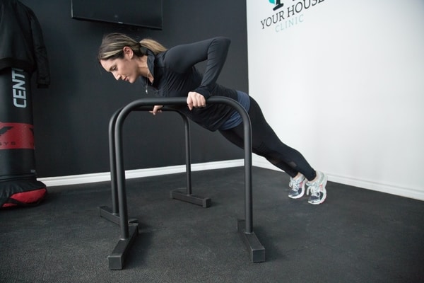 Lady doing a push-up with parallettes