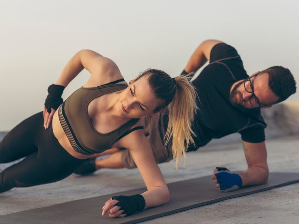 man and woman performing side plank through basic calisthenics training