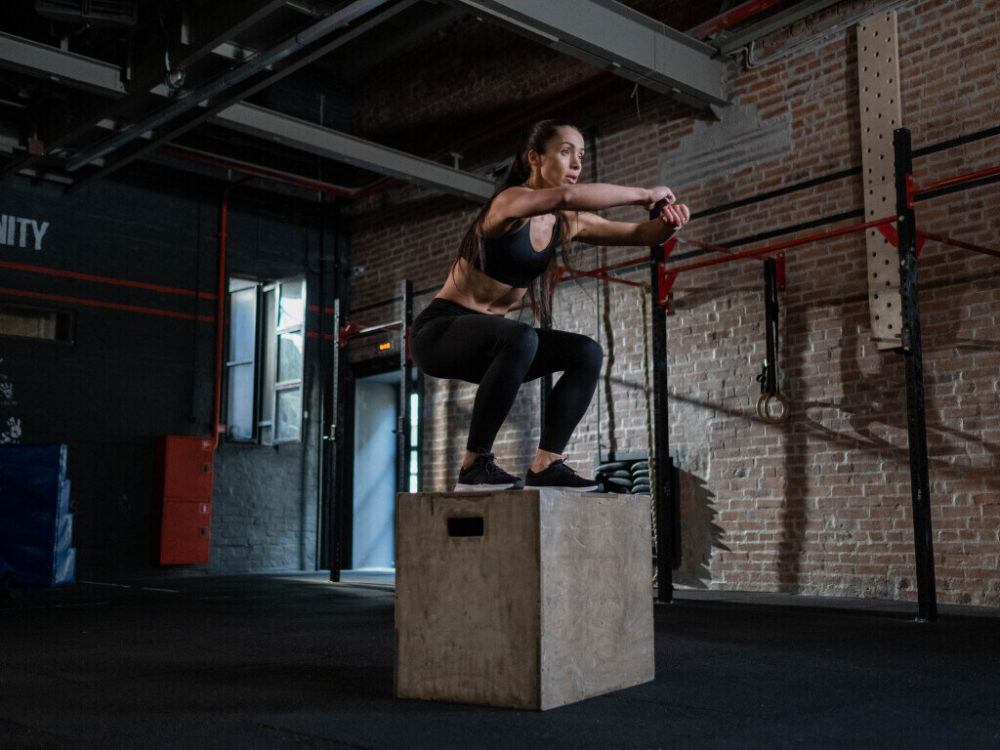 woman doing calisthenics leg workout on plyo box