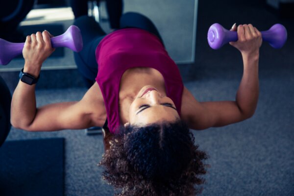 woman using dumbells on weight bench