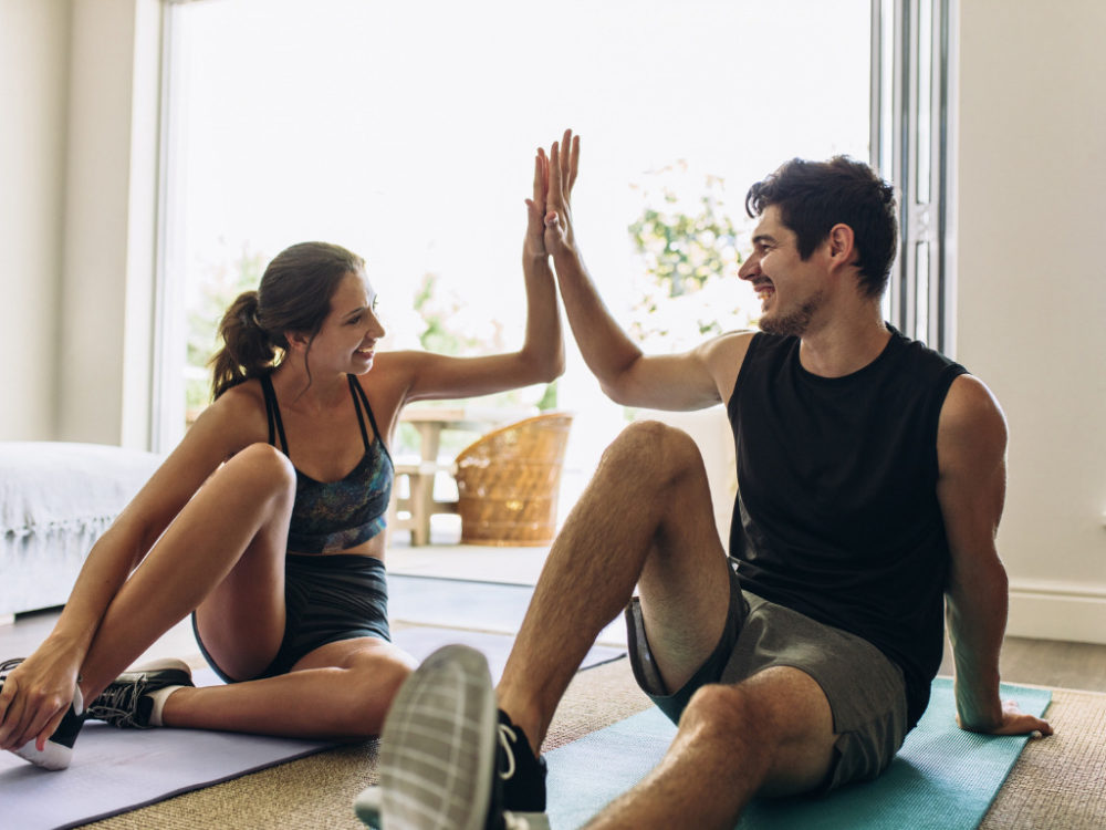 man and woman doing home workouts and high fiving