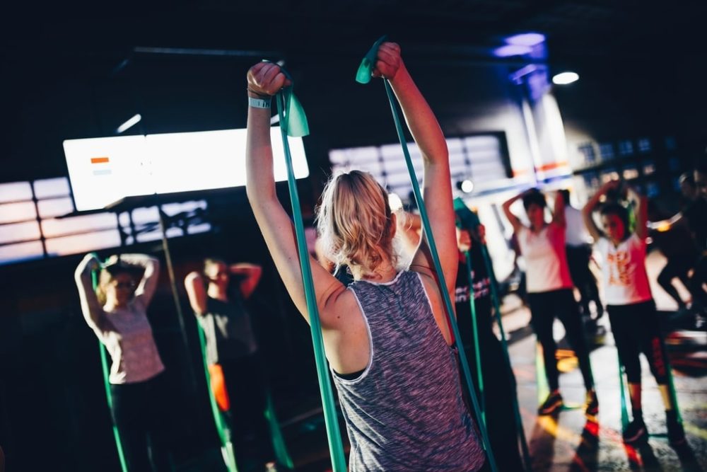 Instructor pulling resistance bands up over back
