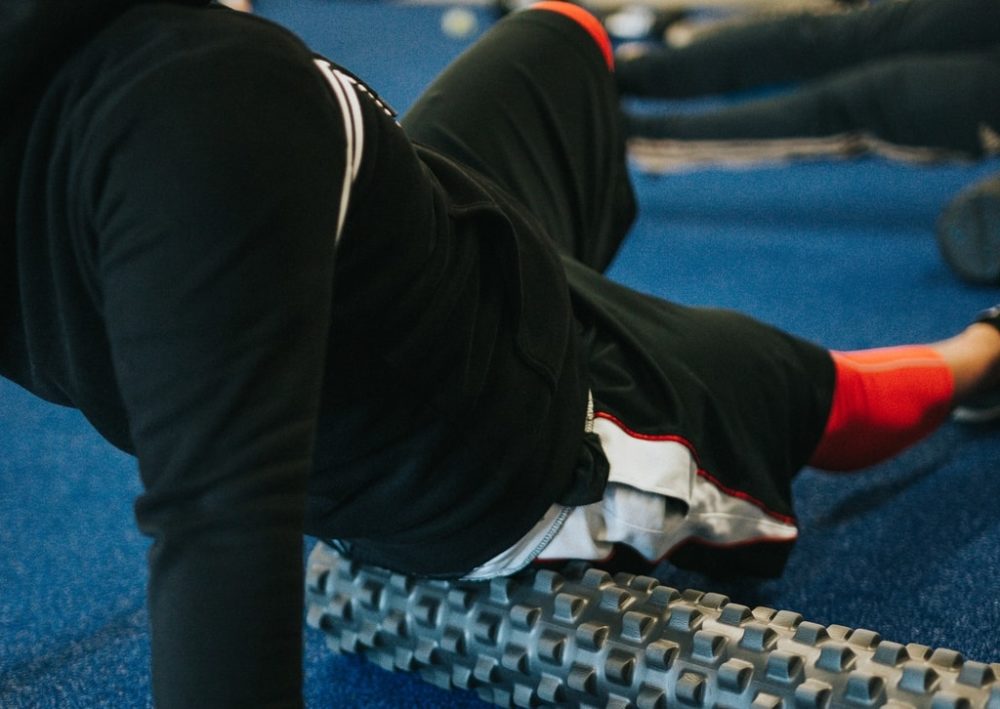 Man on best foam roller on blue gym mat