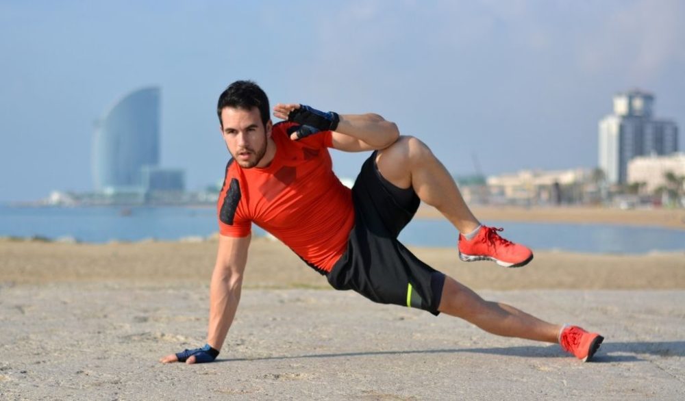 man performing side crunches at the beach