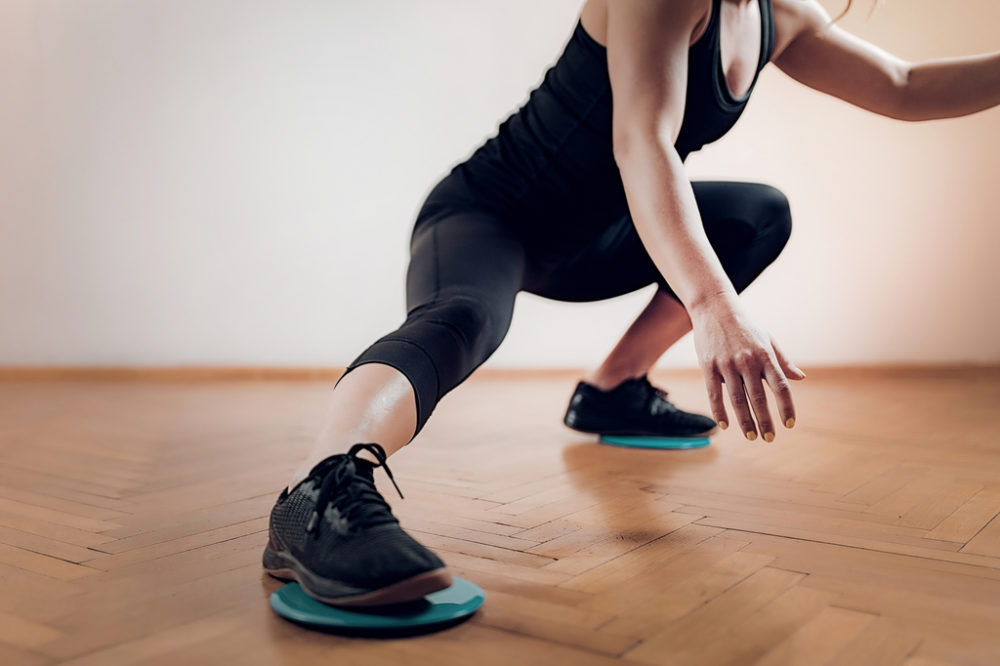 Woman performing lateral lunge with exercise sliders