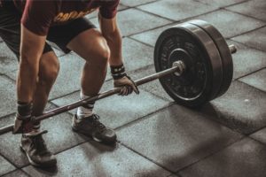 Man gripping bar with gym gloves