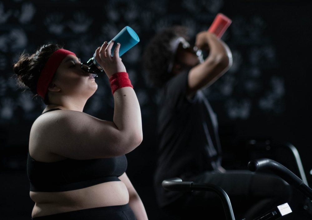 two people drinking water on air bikes