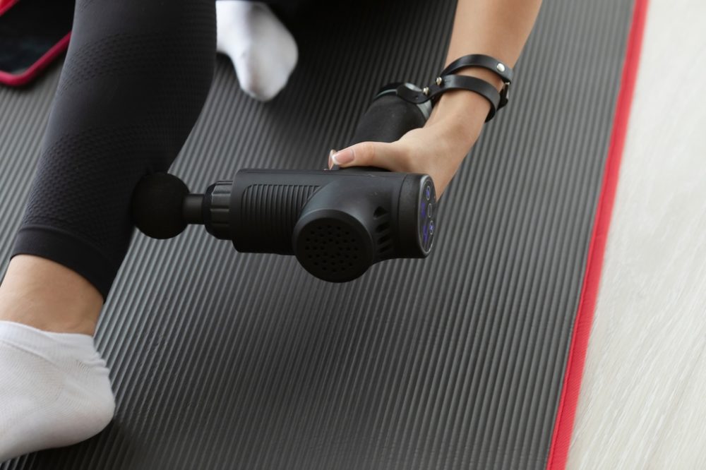 Person using massage gun on ankle and calf