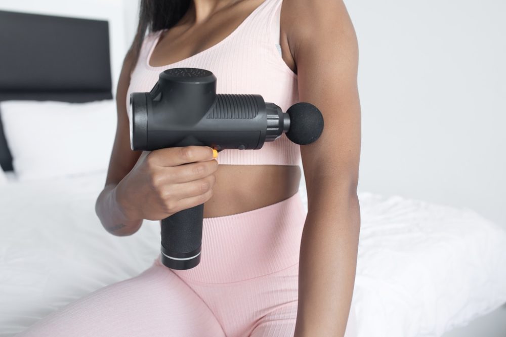 Person using massage gun on bicep