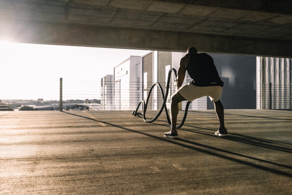 Man using battle ropes in car park