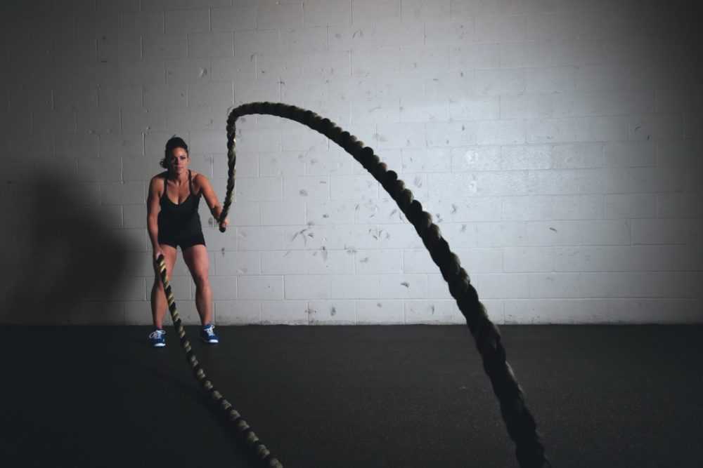 Woman using battle ropes in empty room