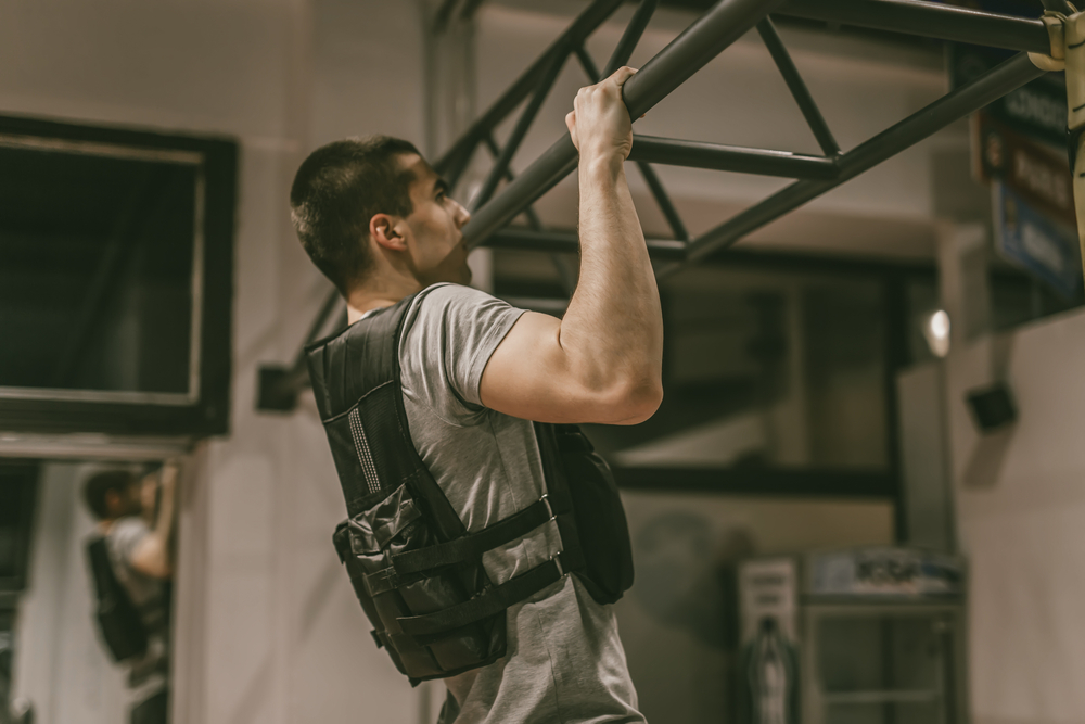 Man wearing weighted vest doing a pull up