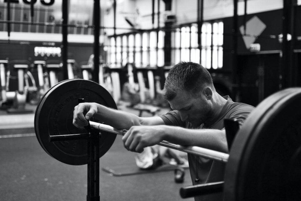 man resting on barbell on squat rack usa home gym