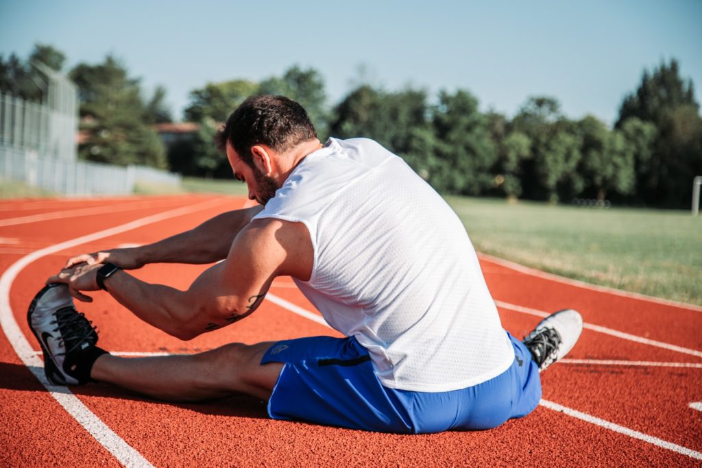 Man stretching with fitness tracker on wrist on running track - fitness tracker comparison image