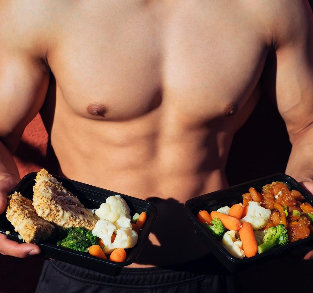 man holding plates with healthy food usa home gym